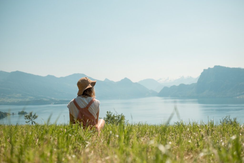 Terapia de Mindfulness. Una persona sentada en un paisaje enfrente de montañas y un lago