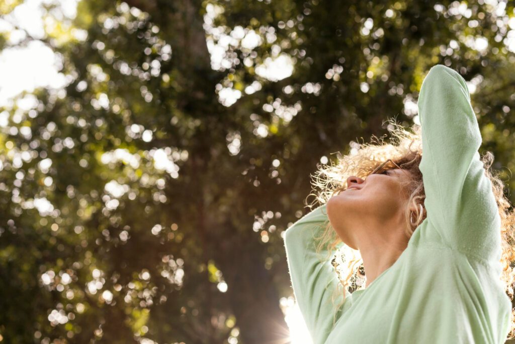 Terapia psicológica de Mindfulness. Una mujer en la naturaleza mirando hacia un arbol