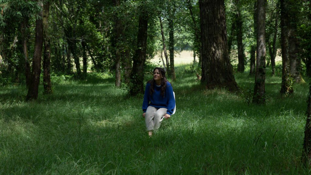 Andrea Guitérrez Psicoterapeuta sentada en una silla en un bosque entre arboles